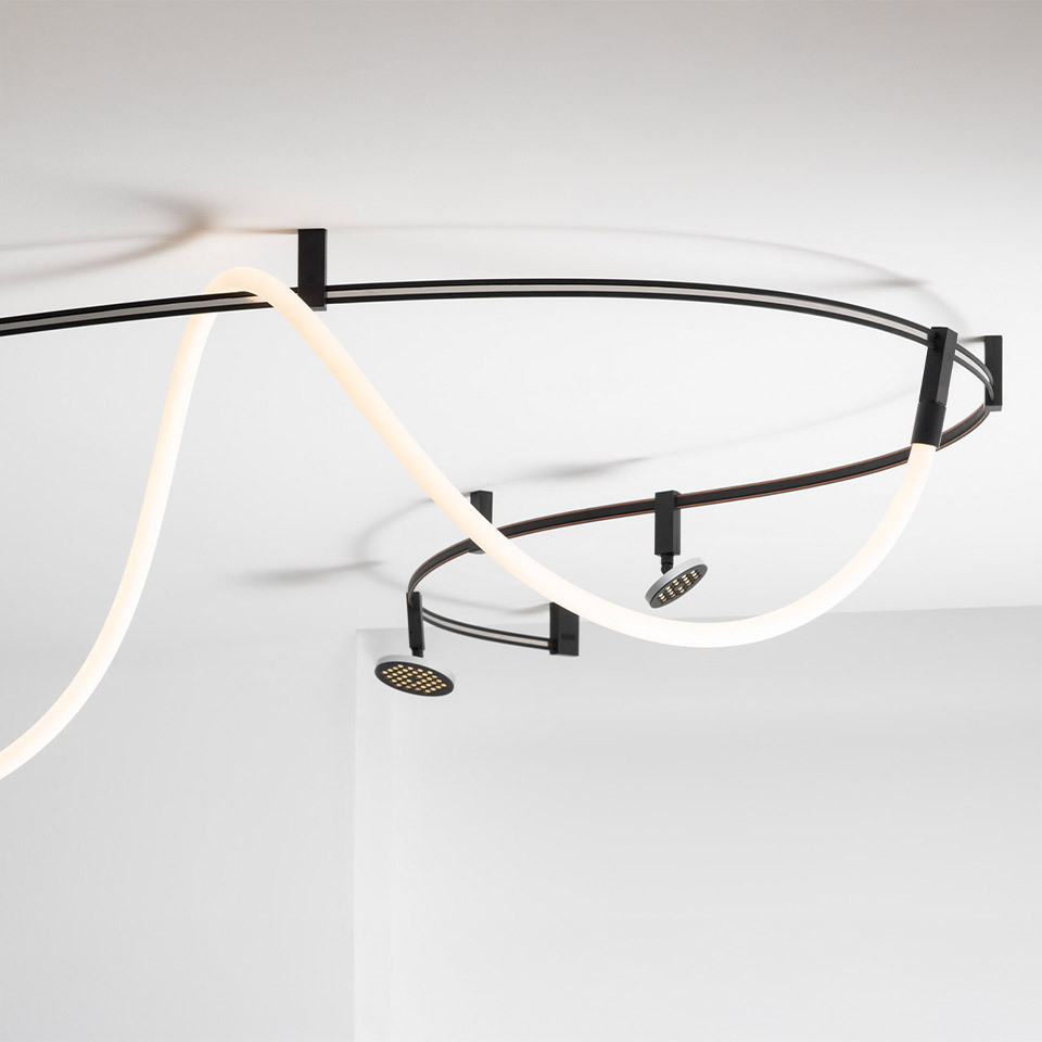 Artemide Sylt ceiling system: dark metal track with sinuous white LED neon tube and two adjustable spotlights mounted on ceiling
