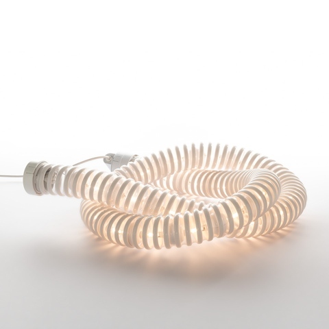 Artemide Boalum lamp: a flexible luminous white tube coiled in a spiral, emitting warm diffused light through ribbed translucent segments
