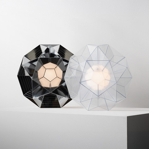 Two Arctic table lamps by Artemide: left in dark mirrored finish, right in transparent, both with geometric faceted polyhedron shade.