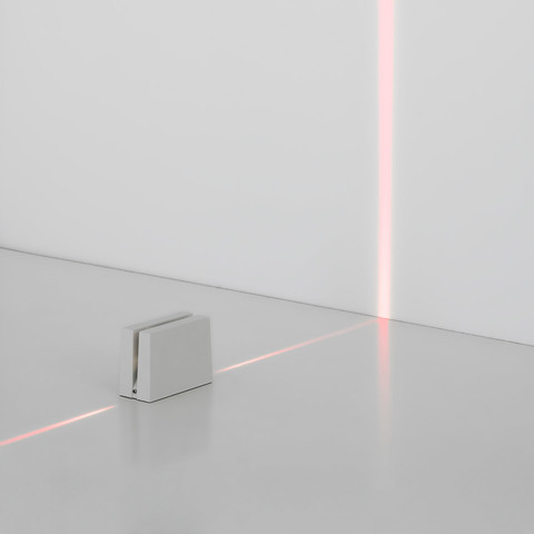 Artemide Antarktikós: unità da pavimento bianca e compatta che emette una sottile linea laser rossa sul pavimento e sulla parete