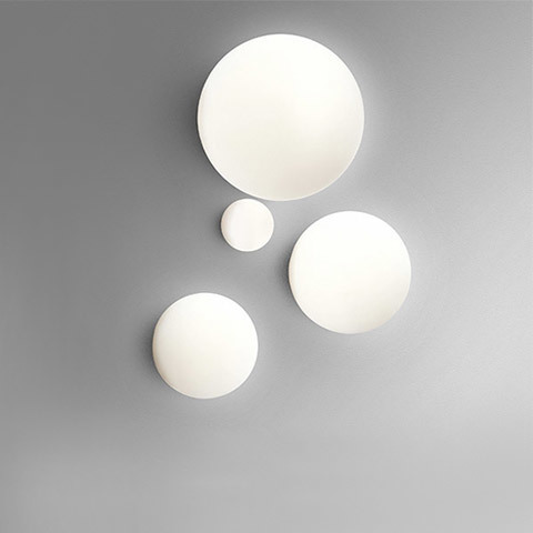 Lampade da parete/soffitto Artemide Dioscuri: quattro diffusori sferici in vetro bianco opalino di diverse dimensioni su parete grigia
