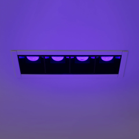 Sharp INTEGRALIS recessed ceiling light with four black modules emitting purple-blue LED light, flush-mounted in white ceiling