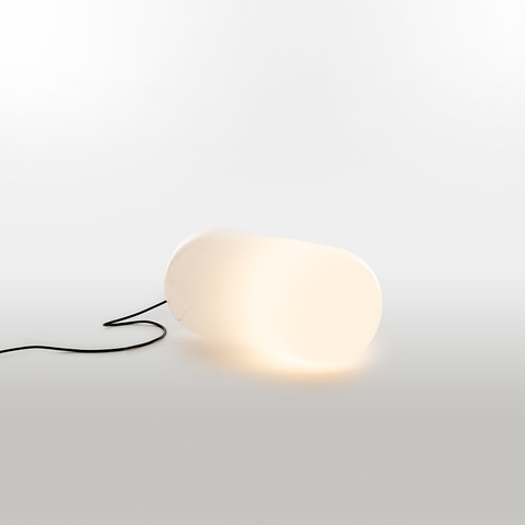 Lampada da terra Artemide Gople Outdoor con diffusore bianco a forma organica di ciottolo che emette luce calda, collegata da un cavo nero