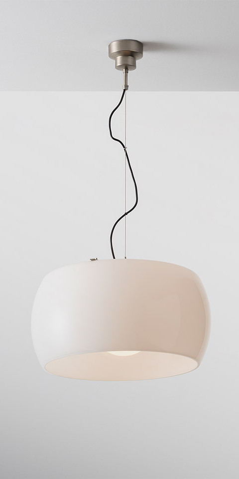Artemide Omega pendant lamp with wide rounded white opal diffuser suspended by a black cord from a brushed metal ceiling rose