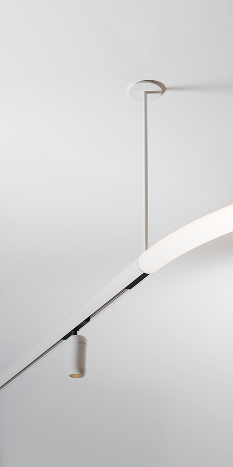 Artemide Gople System: white ceiling-mounted track with a cylindrical pendant spotlight and a curved linear LED diffuser arm