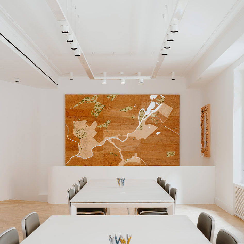 Bright meeting room with white tables, gray chairs, wood artwork on wall, and Artemide recessed spotlights on white ceiling