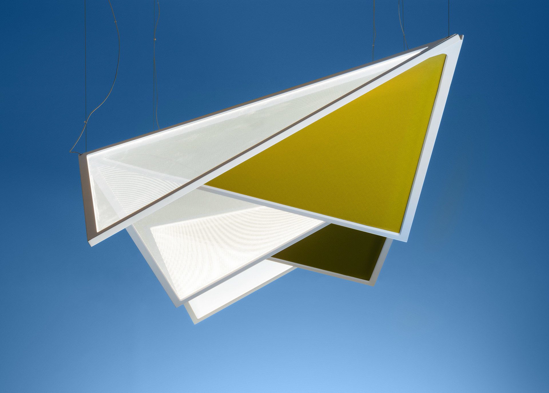 Artemide pendant light with overlapping triangular panels in white and olive yellow, suspended by thin cables against a blue sky