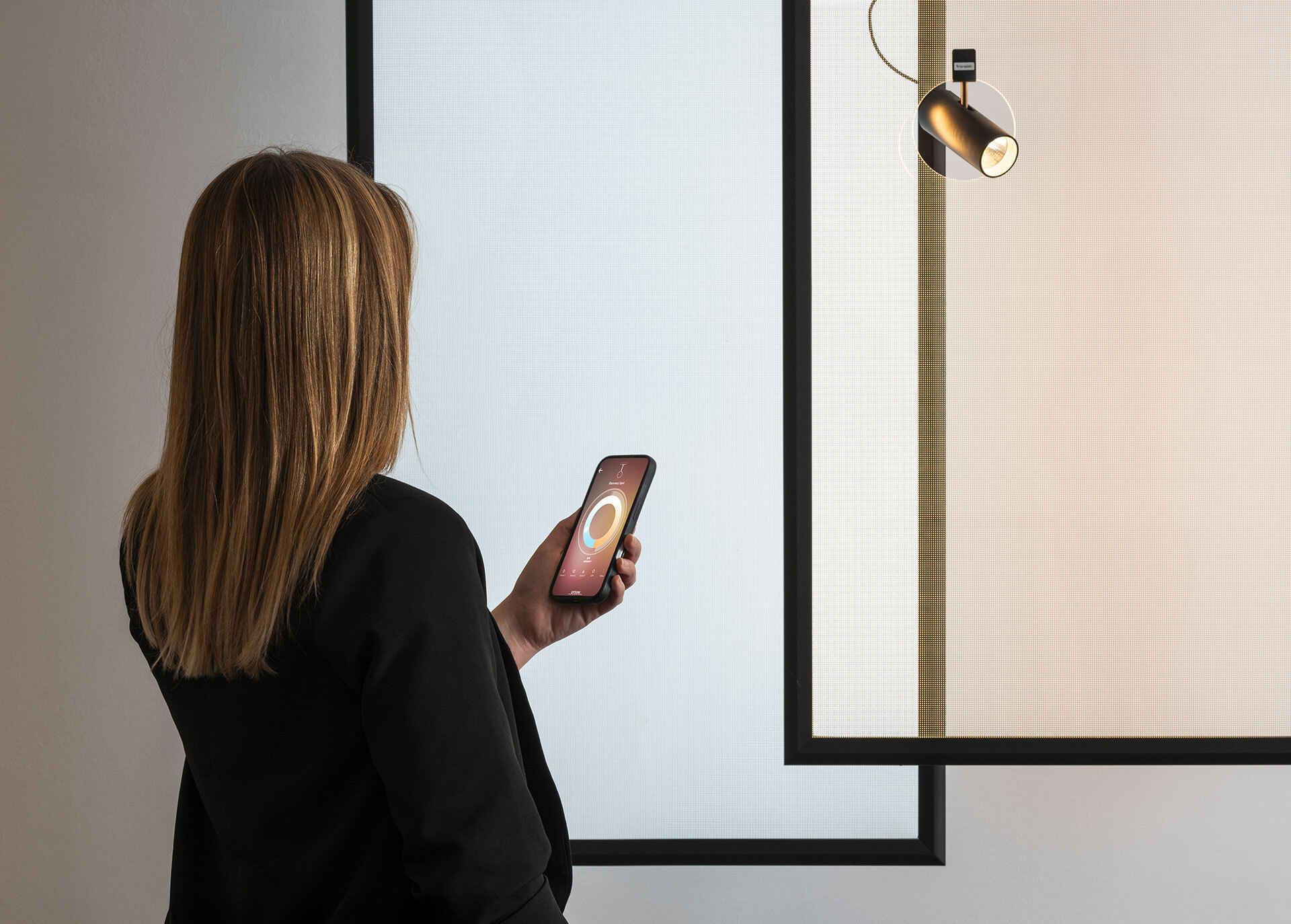 Donna regola un faretto tramite app su smartphone.