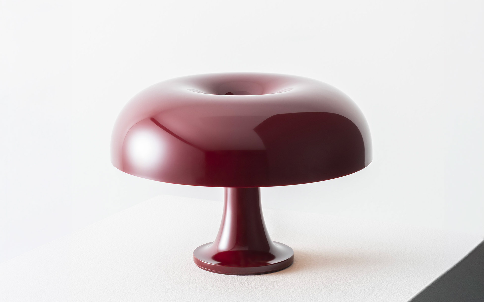 Lampada Nessino bordeaux su piedistallo bianco.