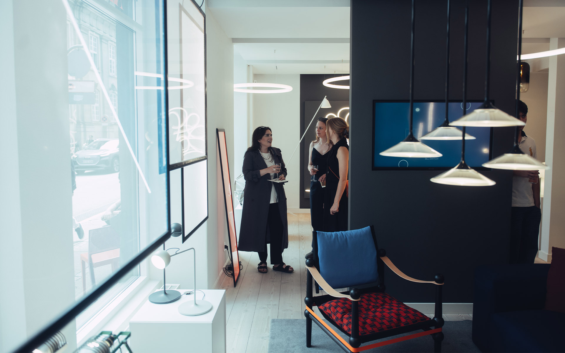 Due donne in consulenza in uno showroom Artemide con lampade a sospensione, da tavolo e LED circolari in un interno moderno.