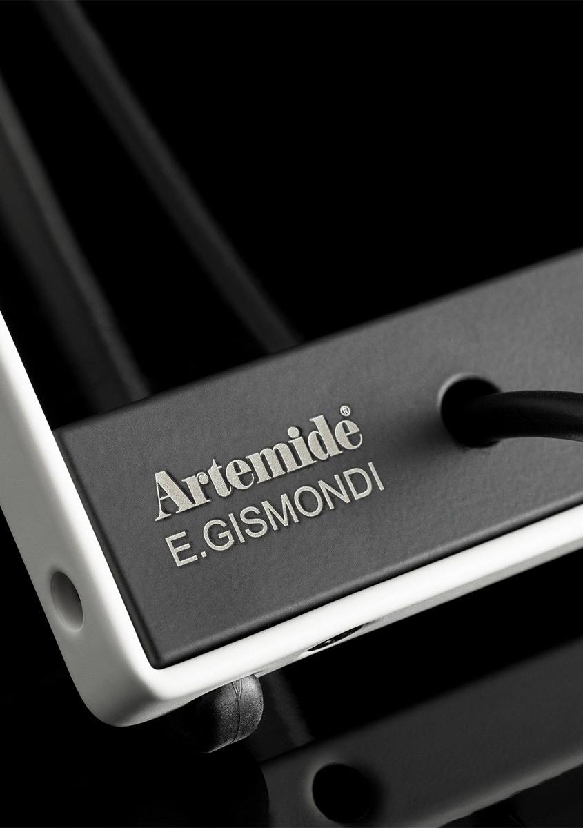 Dettaglio della base della lampada Sintesi con la scritta "Artemide, E. Gismondi", su sfondo nero.