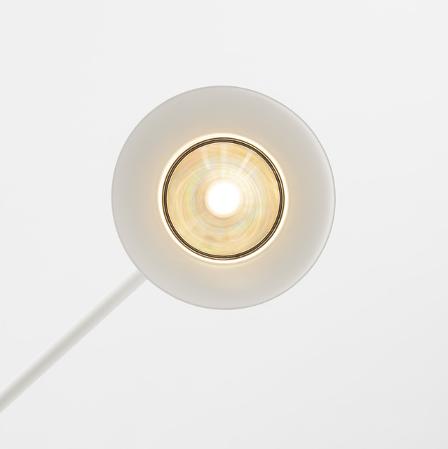 Primo piano di una testa lampada circolare bianca vista dall'alto, con bulbo LED centrale, riflettore iridescente e luce calda
