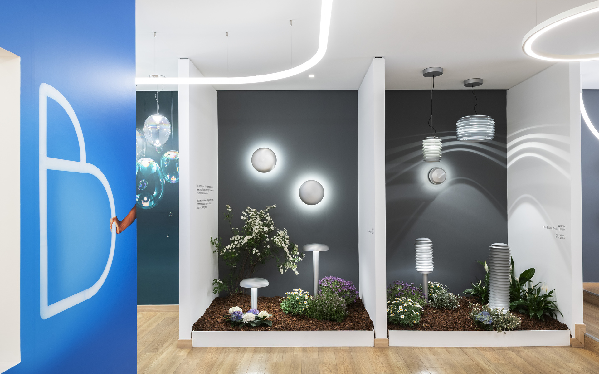Esposizione showroom Artemide con illuminazione outdoor: luci da parete a globo, lampade a sospensione e segnapasso tra le piante