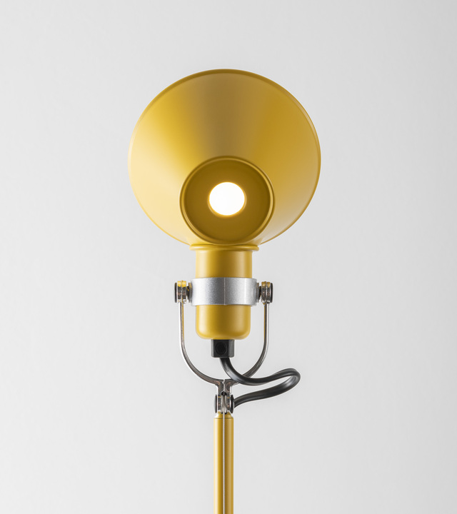Dettaglio del diffusore della lampada Tolomeo in alluminio verniciato giallo, con snodo metallico orientabile e luce accesa su sfondo chiaro.