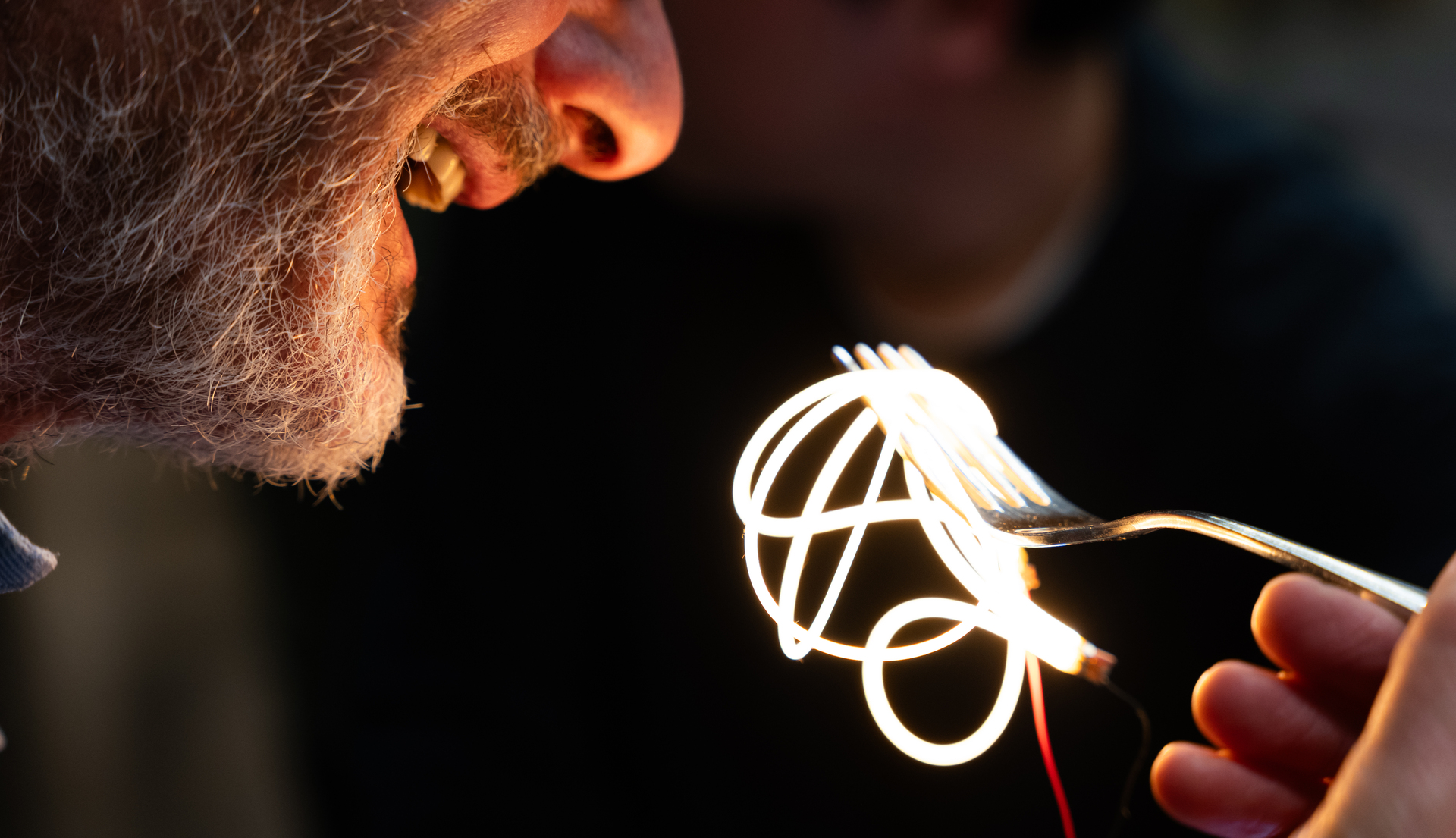 Immagine surreale di una persona che mangia spaghetti luminosi.