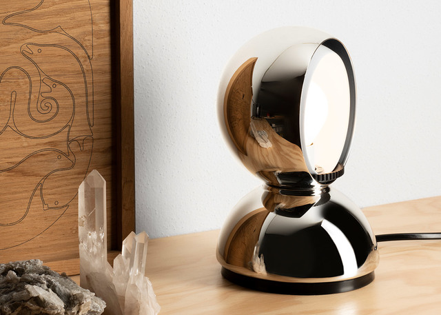 Artemide Eclisse table lamp in polished chrome finish, spherical adjustable shade on round base, displayed on a wooden surface