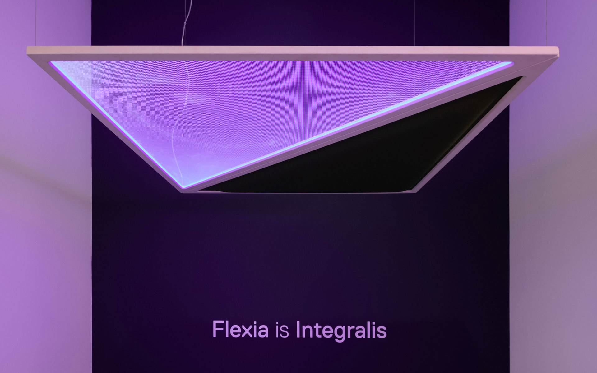 Lampada a sospensione Artemide Flexia Integralis che emette luce viola, con pannello in vetro specchiato angolare che riflette il nome del brand