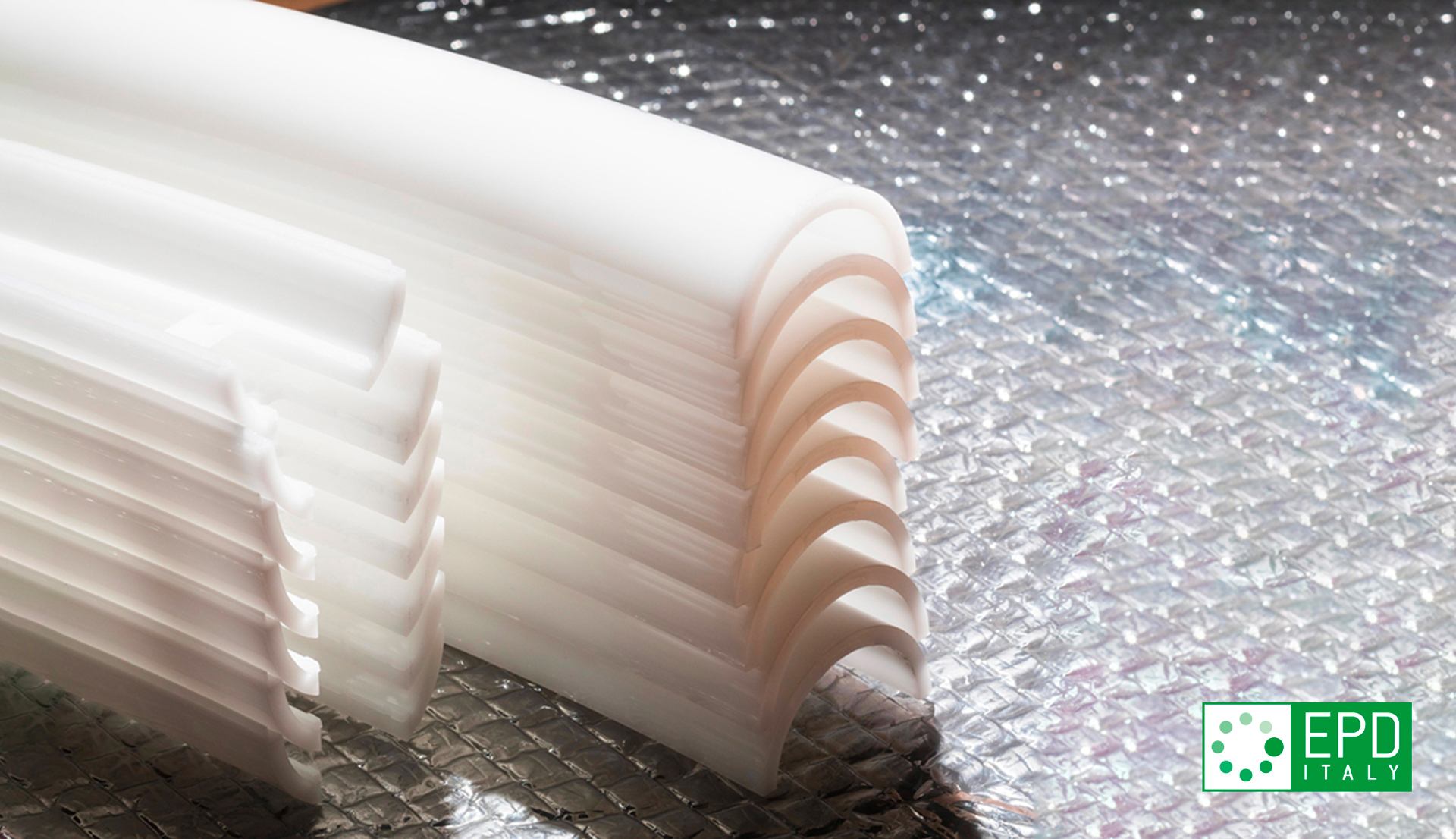 Primo piano di componenti diffusori in opale bianco con texture nervata, impilati insieme, che mostrano il materiale diffondente usato nelle lampade Artemide