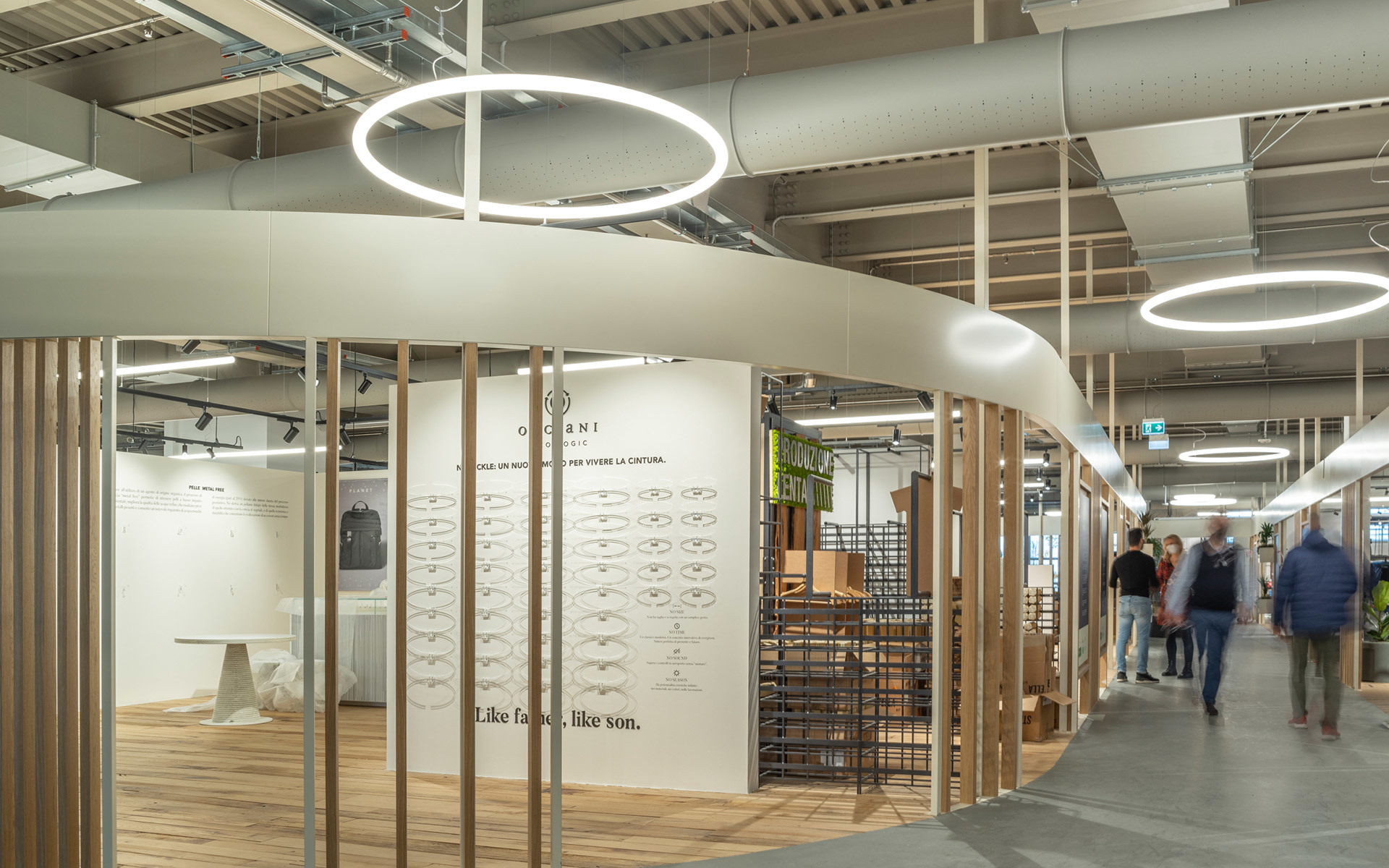 Spazio commerciale con lampade a sospensione circolari Artemide che illuminano una boutique di moda con colonne in legno e pareti espositive.