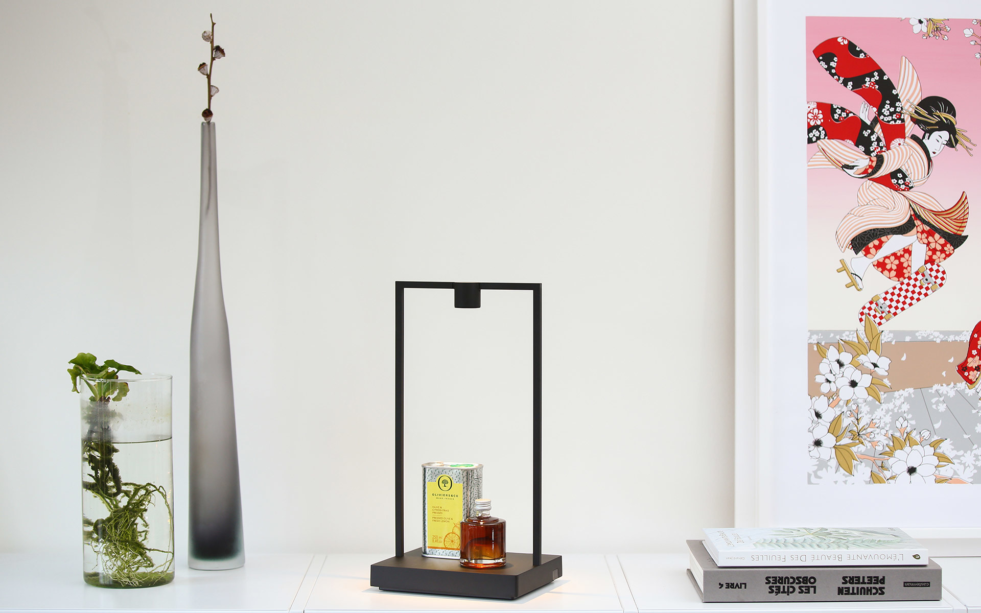Lampada da tavolo con struttura rettangolare nera e striscia LED, esposta su uno scaffale bianco accanto a un vaso in vetro e oggetti decorativi