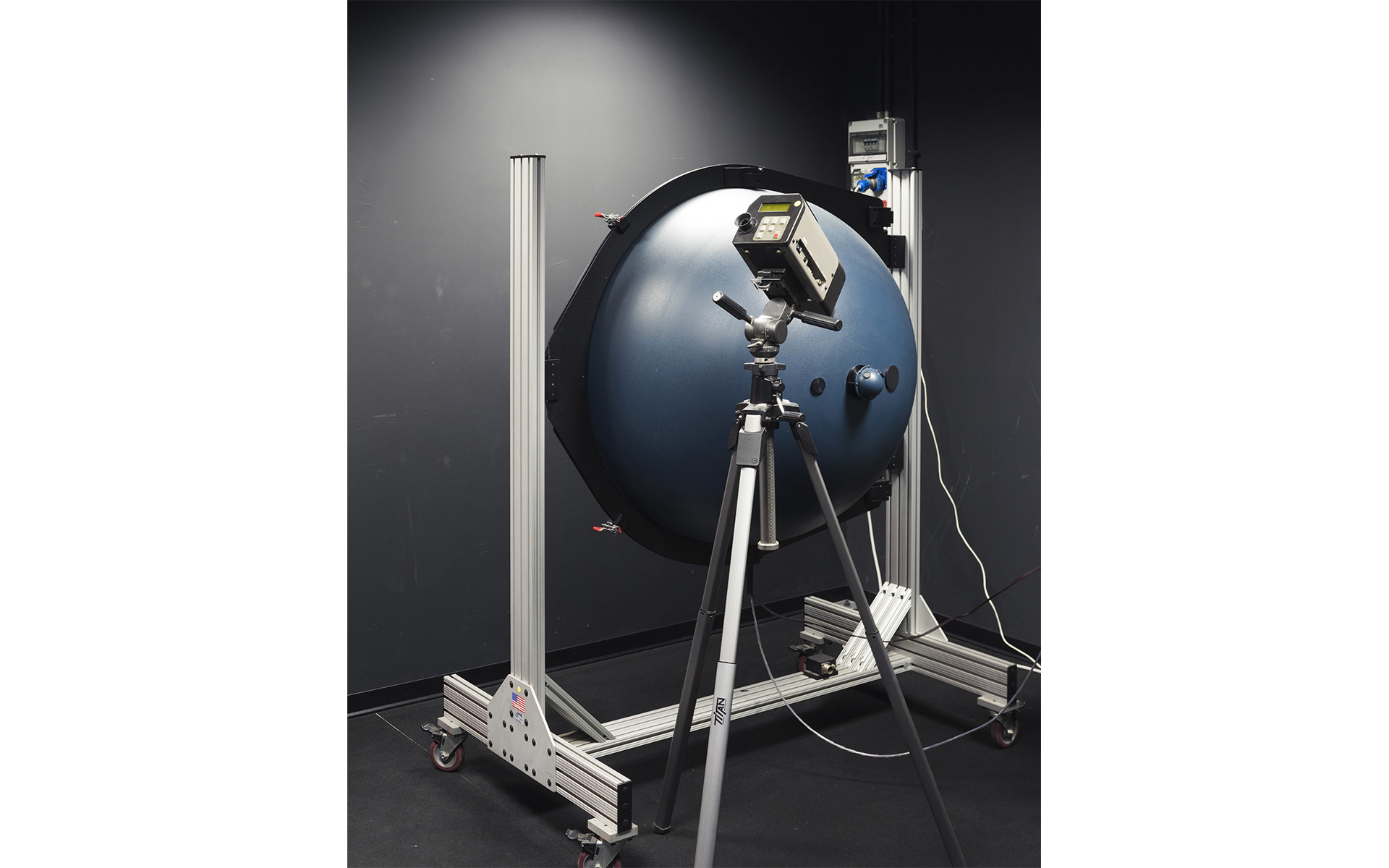 Fotometro a sfera integratrice su treppiede utilizzato per misurare il flusso luminoso e le prestazioni ottiche di apparecchi illuminanti in laboratorio.