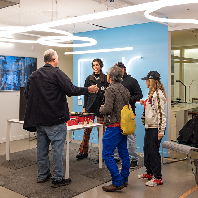 Persone in networking in uno showroom moderno sotto lampade a sospensione circolari LED Artemide che illuminano lo spazio aperto.