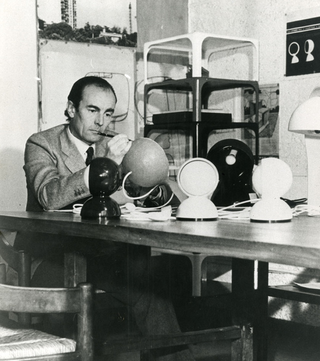 Designer studying multiple Eclisse table lamp prototypes in black and white on a desk, in a design studio, 1960s
