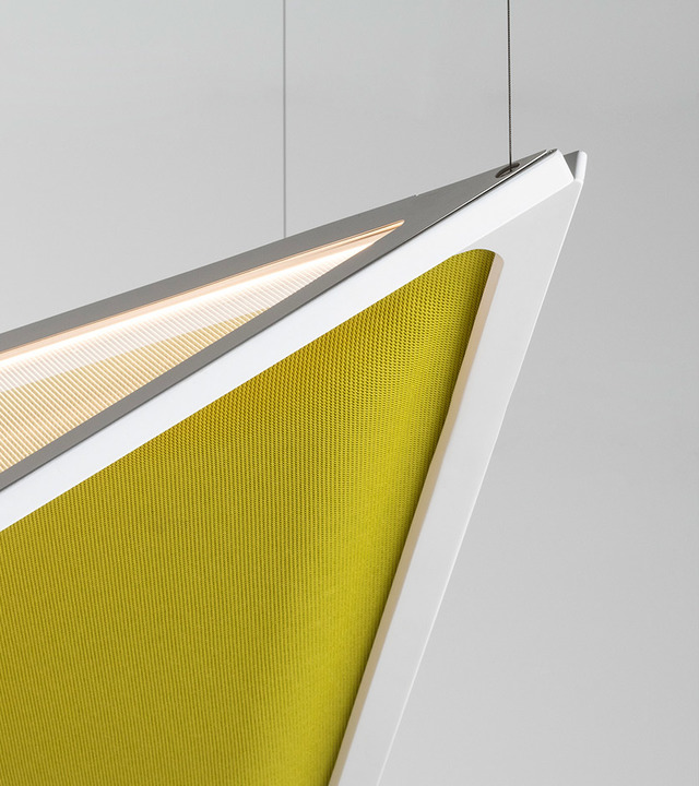 Primo piano di una lampada a sospensione geometrica con struttura angolare bianca, striscia LED calda e pannello fonoassorbente in rete giallo-verde