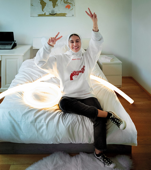 Persona seduta su un letto circondata da tubi LED flessibili Artemide che formano un anello luminoso sulla biancheria bianca