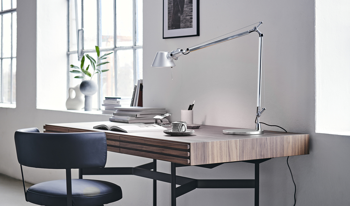 Lampada da tavolo Artemide Tolomeo in alluminio su una moderna scrivania in legno in un luminoso home office con sedia e oggetti decorativi