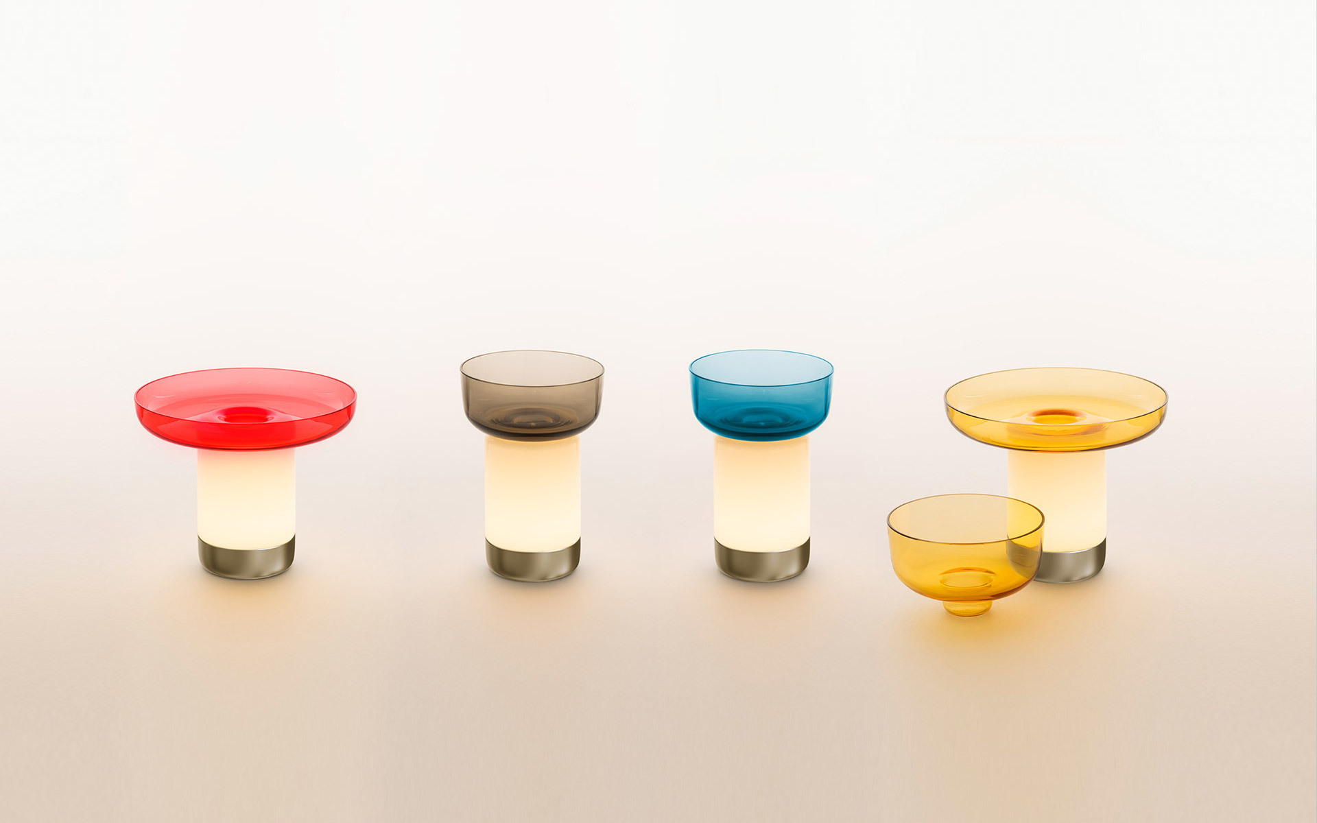 Quattro lampade portatili Artemide con basi bianche luminose, piedi in metallo e ciotole in vetro colorato in rosso, fumé, teal e ambra