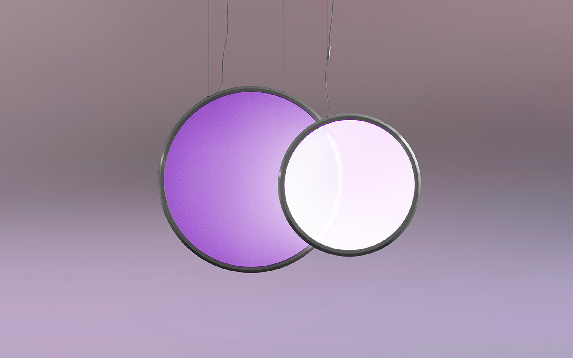 Due lampade a sospensione circolari sovrapposte con cornici scure: sinistra emette luce viola, destra emette luce bianco-rosa, sospese da sottili cavi
