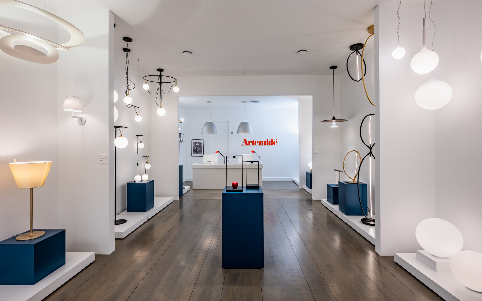Showroom Artemide con collezione di illuminazione: lampade a sospensione, da parete e da tavolo con globi in vetro bianco e design circolari su pavimento in legno scuro