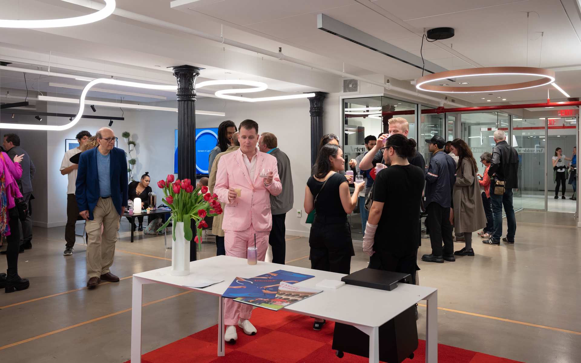 Evento Artemide: ospiti in uno spazio moderno con lampade a sospensione sinuose bianche e circolari rosse.