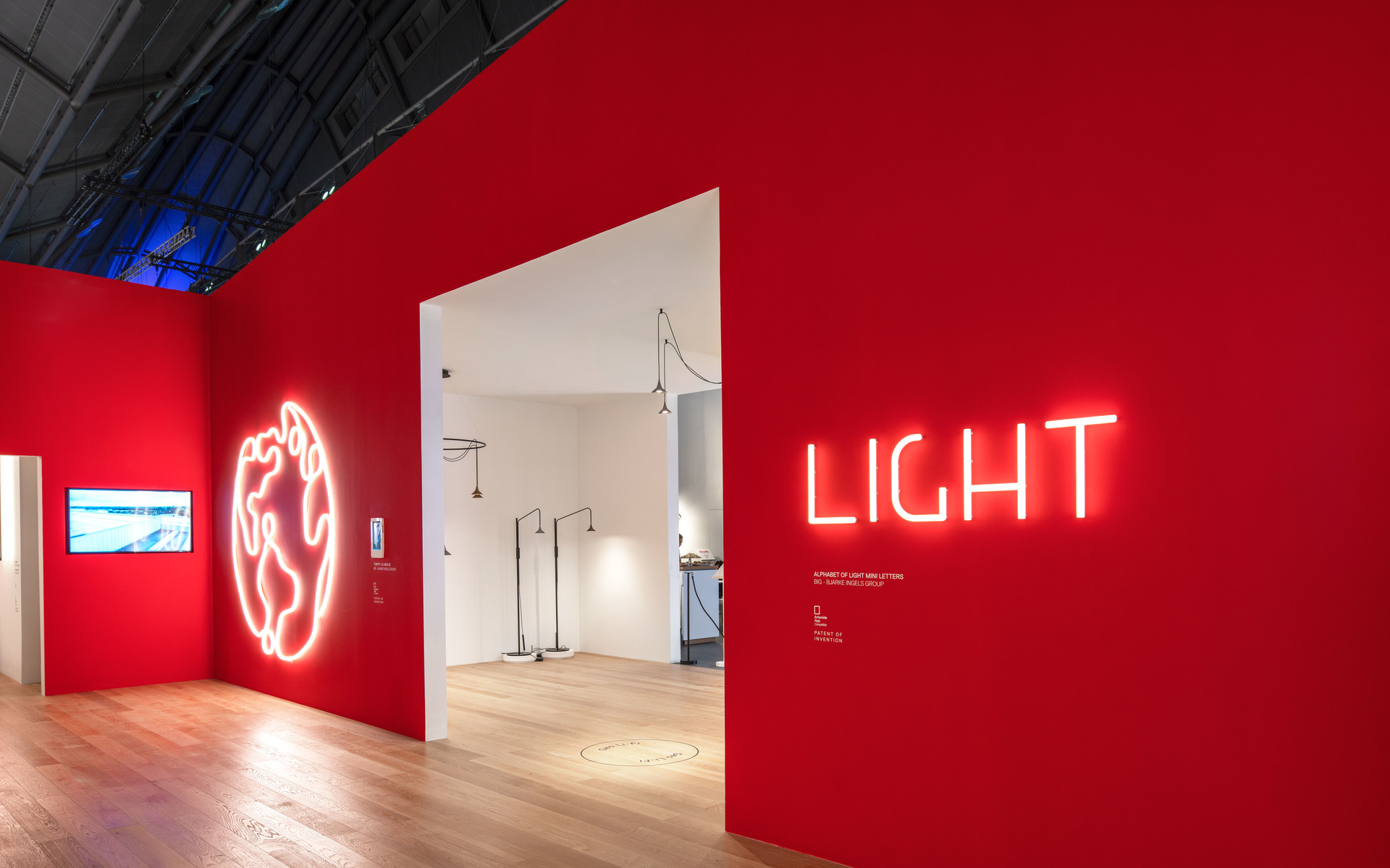 Exhibition entrance with red walls, neon 'LIGHT' sign, glowing brain sculpture, and Artemide floor lamps visible through doorway