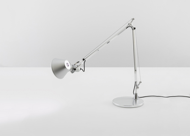 Lampada da tavolo Artemide Tolomeo in alluminio lucidato con braccio articolato regolabile, paralume conico e base circolare su superficie bianca