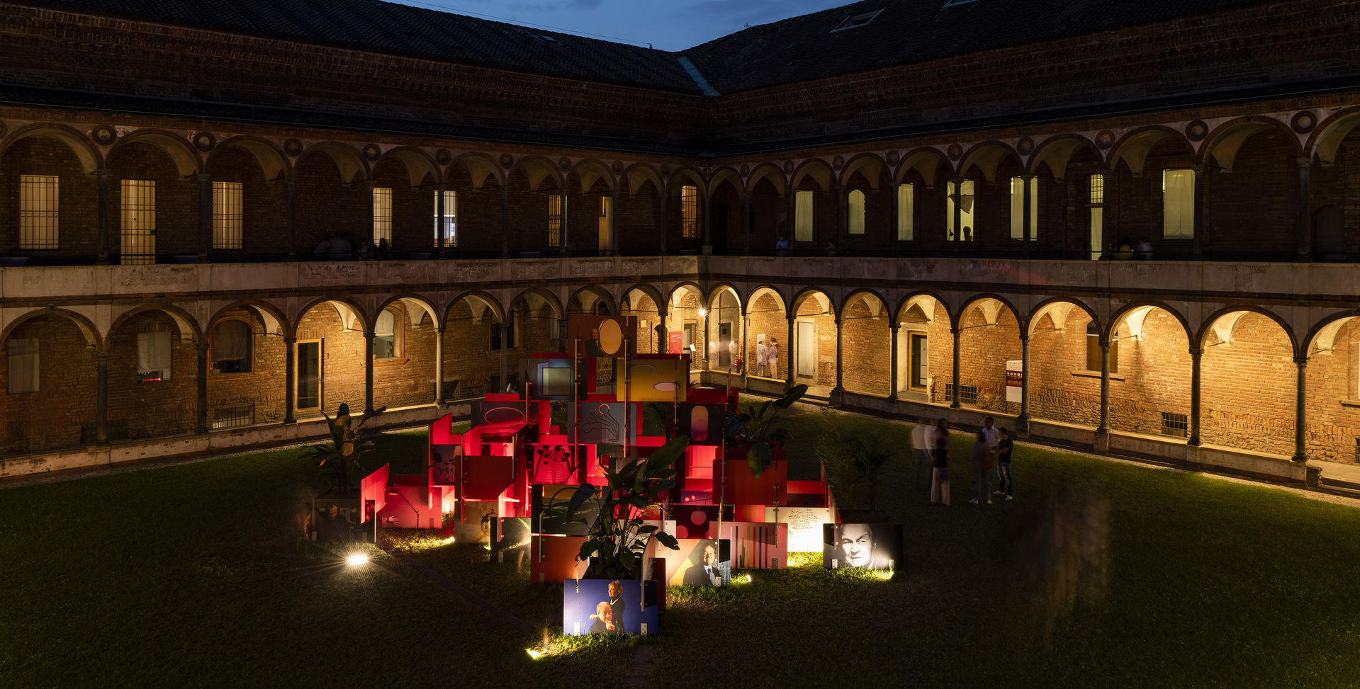 Artemide lighting installation in a historic arcaded courtyard at night, with colorful illuminated geometric structures on the lawn