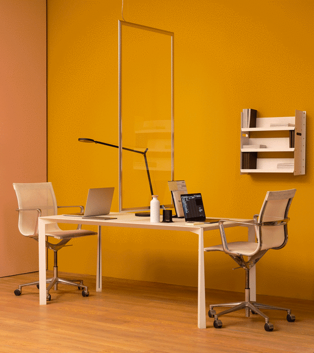 Postazione ufficio moderna con due sedie a una scrivania bianca condivisa, lampada da tavolo Artemide Tolomeo e una luce a sospensione rettangolare sopra.