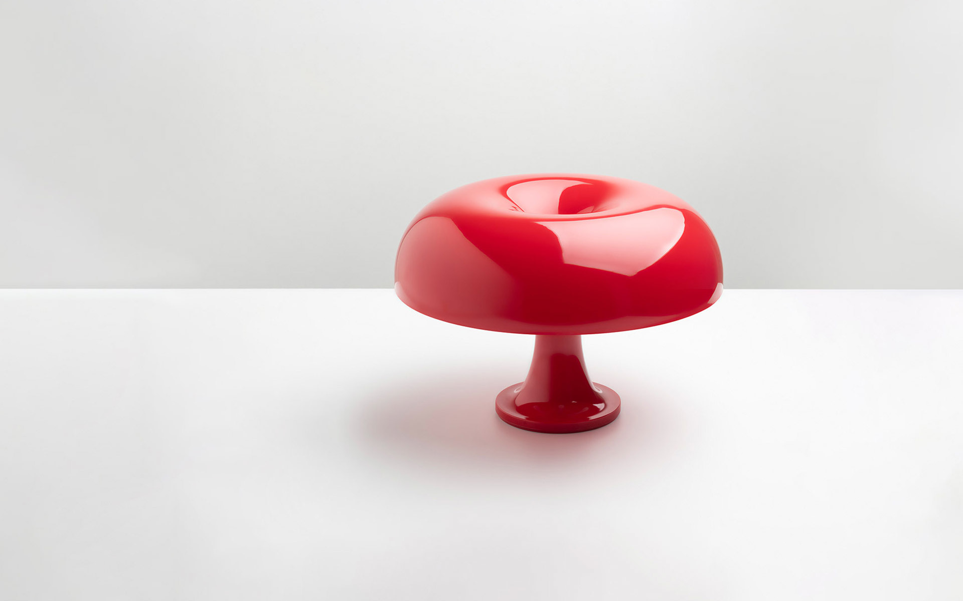 Lampada da tavolo Artemide Nessino in rosso lucido, con paralume a forma di fungo su una base a piedistallo sottile