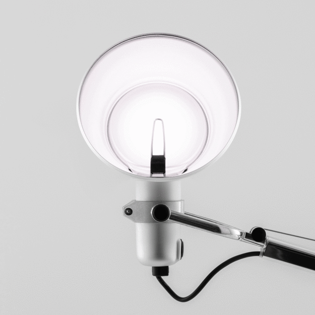 Primo piano della testa della lampada Artemide Tolomeo: paralume conico bianco con perno di regolazione, snodo orientabile e braccio cromato articolato con cavo