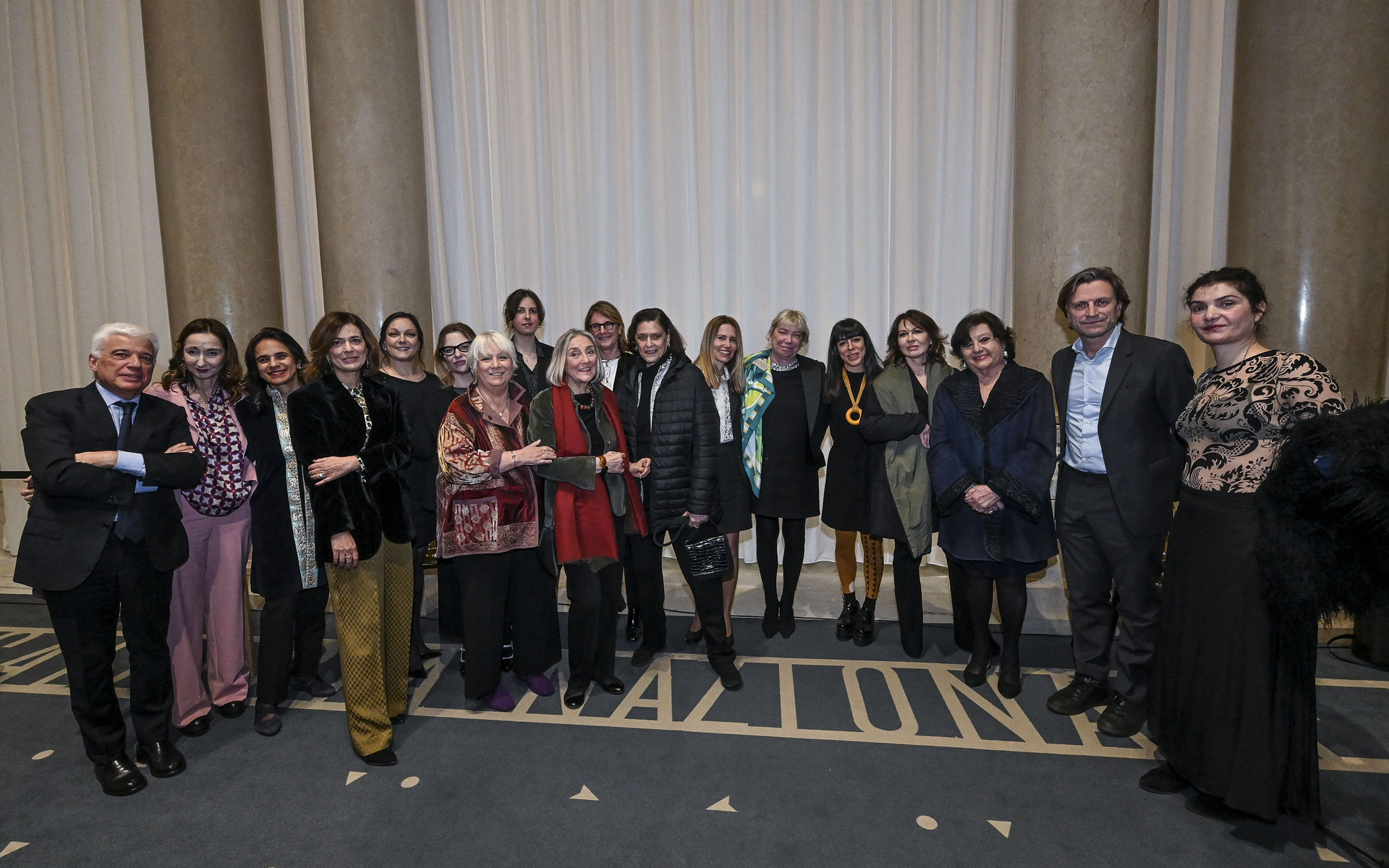 Gruppo di circa venti professionisti in posa per una foto di gruppo formale in una sala elegante.