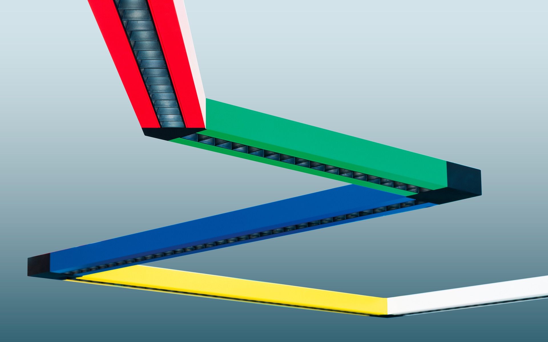 Sistema di illuminazione LED lineare modulare Artemide con quattro segmenti angolari in rosso, verde, blu e giallo, a formare uno schema a zigzag