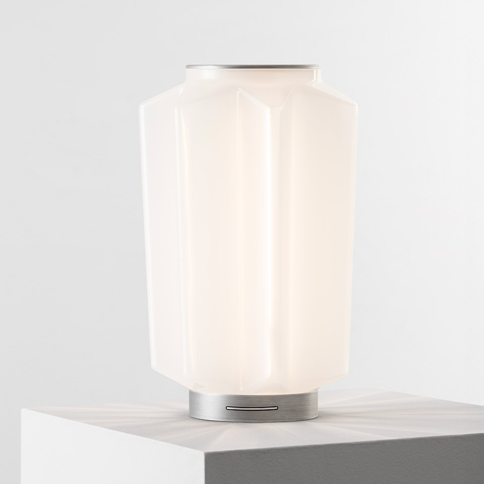 Lampada da tavolo Artemide Auralia con diffusore in vetro opalino bianco sfaccettato e base in alluminio spazzolato su superficie in marmo