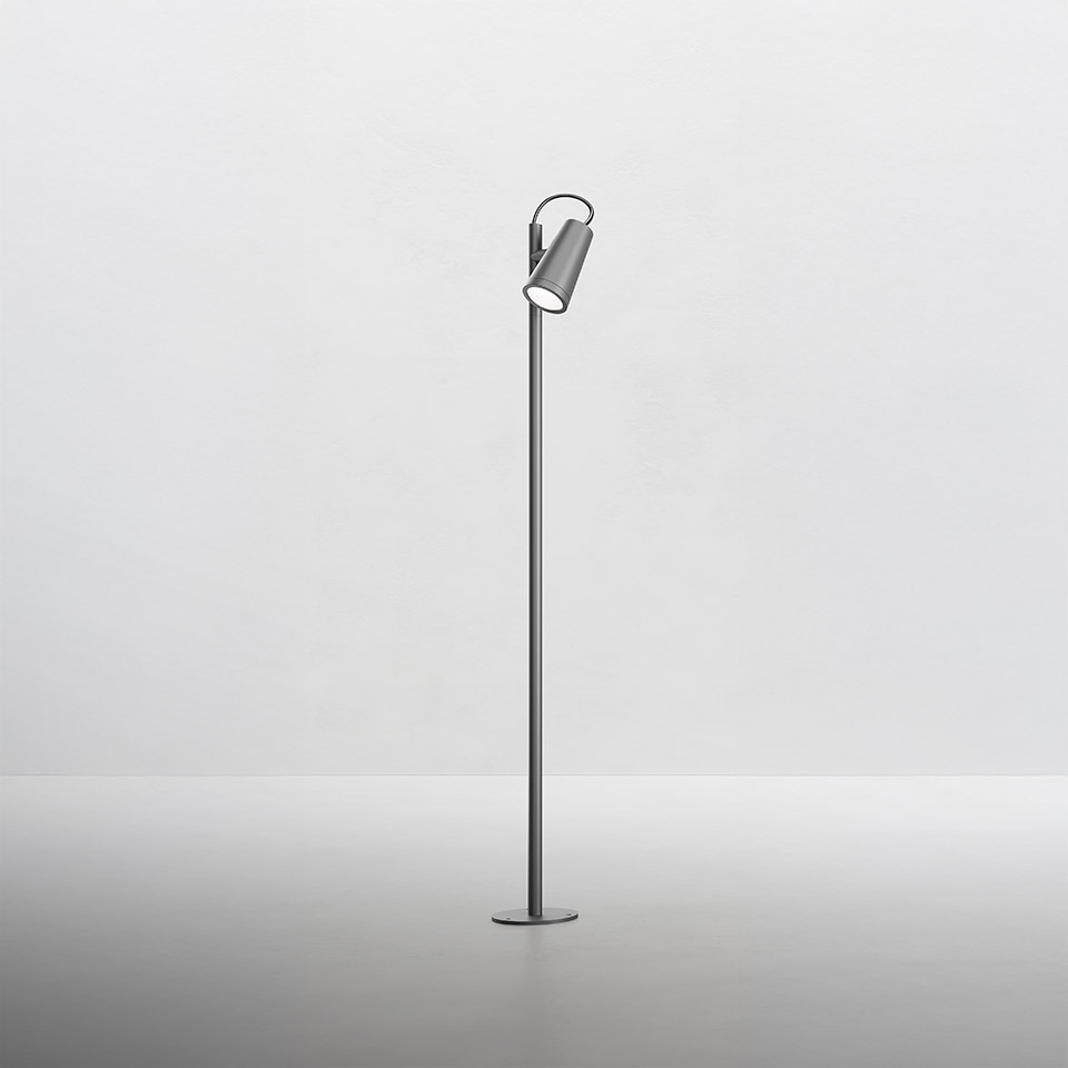 Lampada da terra Artemide Conus: sottile palo metallico con testa cilindrica orientabile in finitura grigia, montata su base circolare