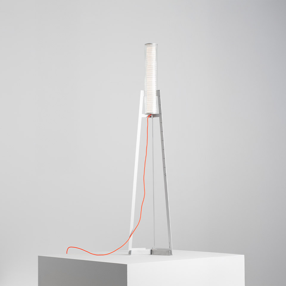 Artemide Criosfera table lamp: white triangular metal frame with cylindrical ribbed diffuser on top and bright orange power cord