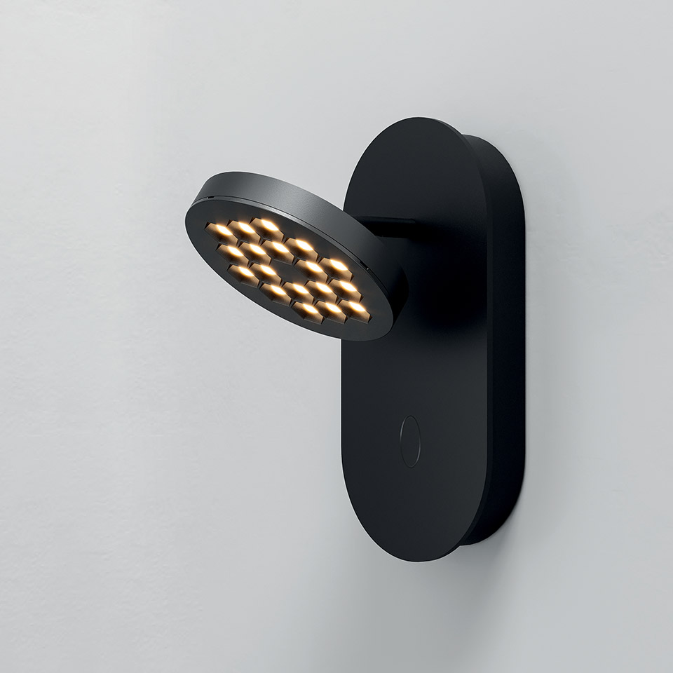 Lampada da parete Artemide Helgoland nera con testa LED circolare orientabile e riflettori dorati, montata su base ovale