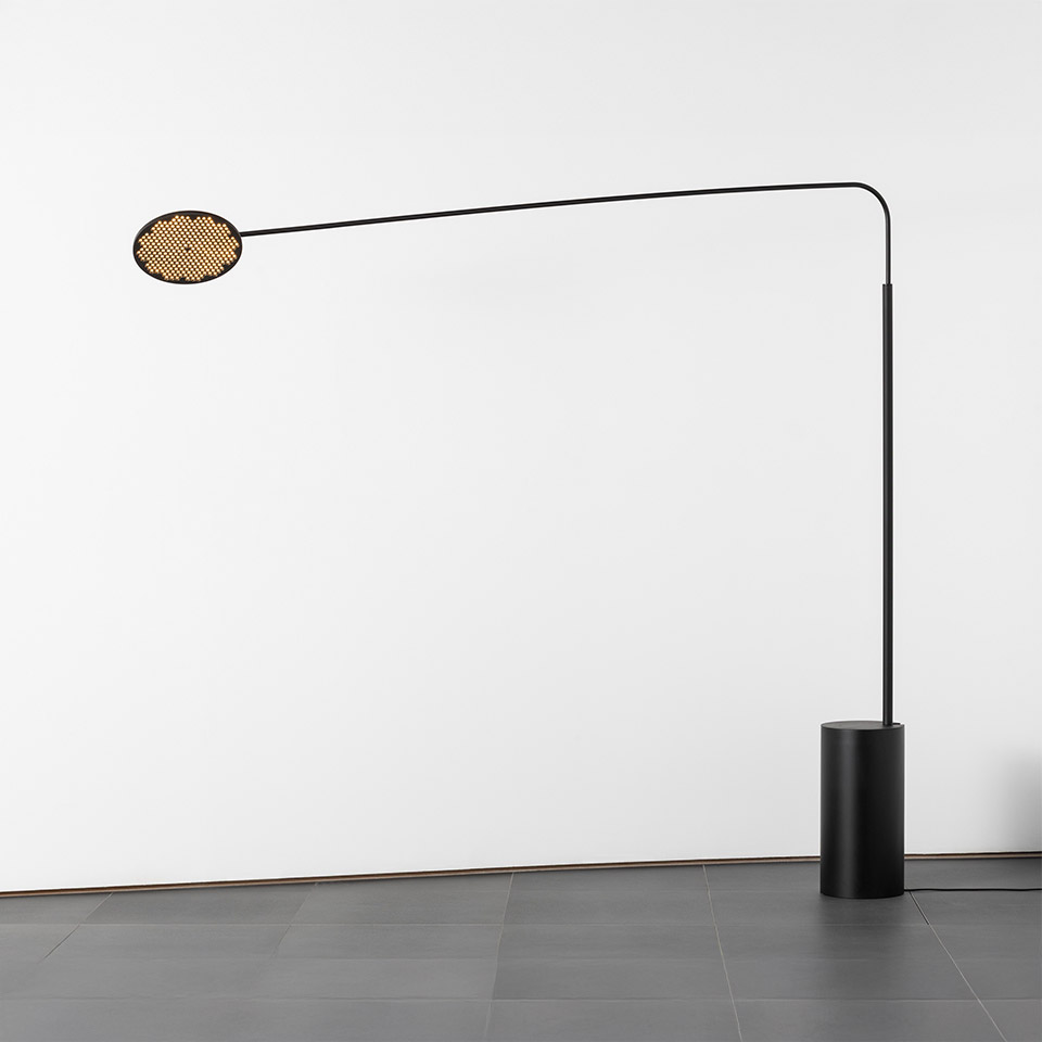 Lampada da terra Artemide Helgoland: stelo ad arco nero con base cilindrica, diffusore ovale forato dorato in posizione orizzontale