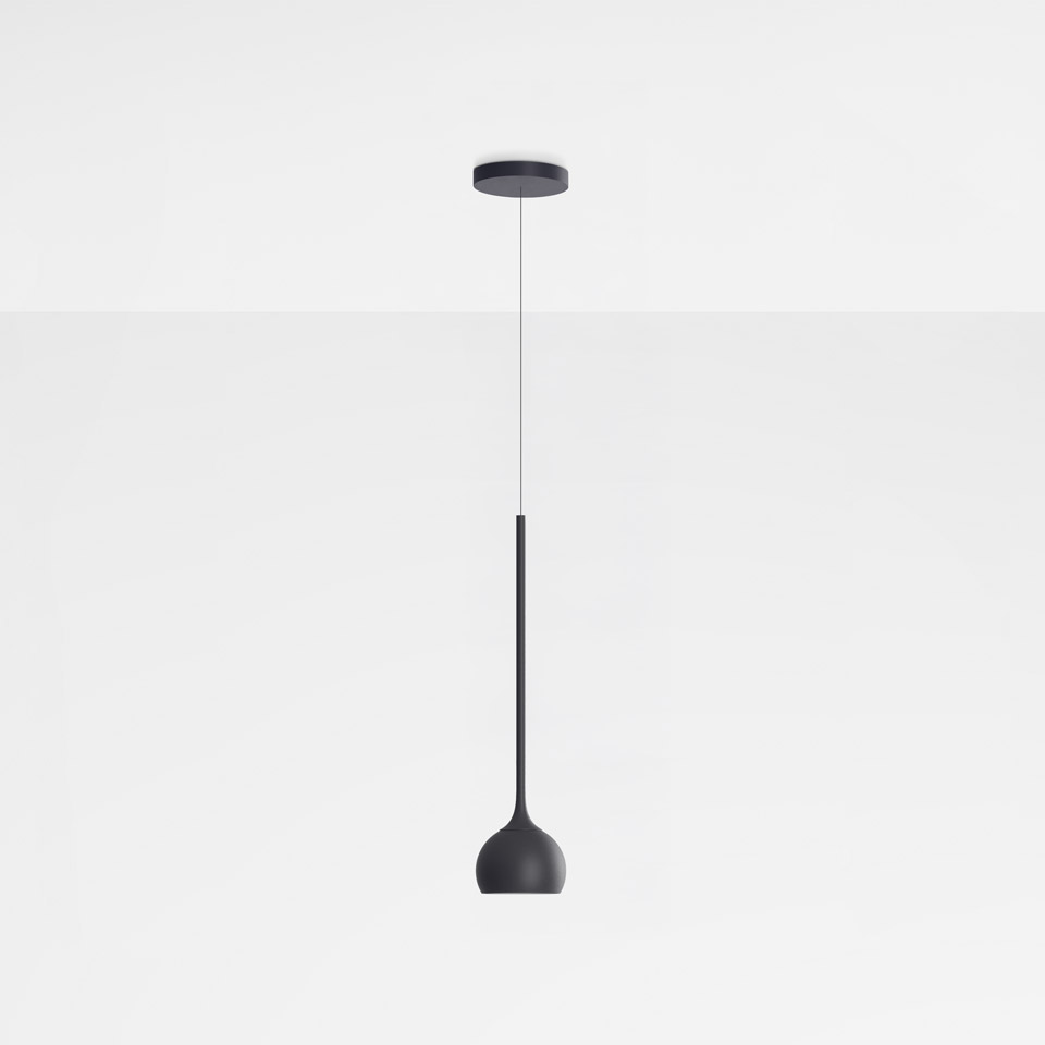 Lampada a sospensione Artemide Ixa in nero, con stelo sottile e paralume a campana arrotondata, appesa a un rosone circolare a soffitto.