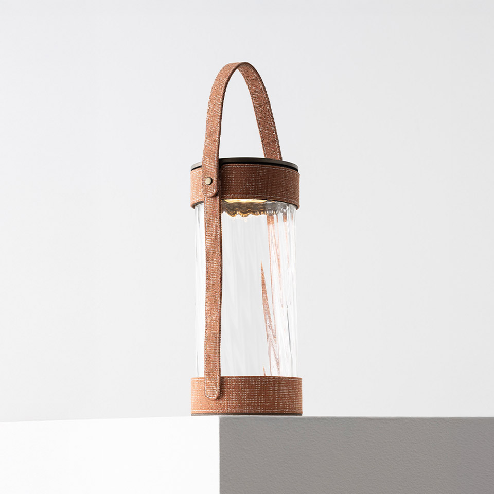 Lampada portatile Artemide Laya: diffusore in vetro cilindrico nervato con luce LED calda, sorretto da un manico in cinghia di pelle marrone