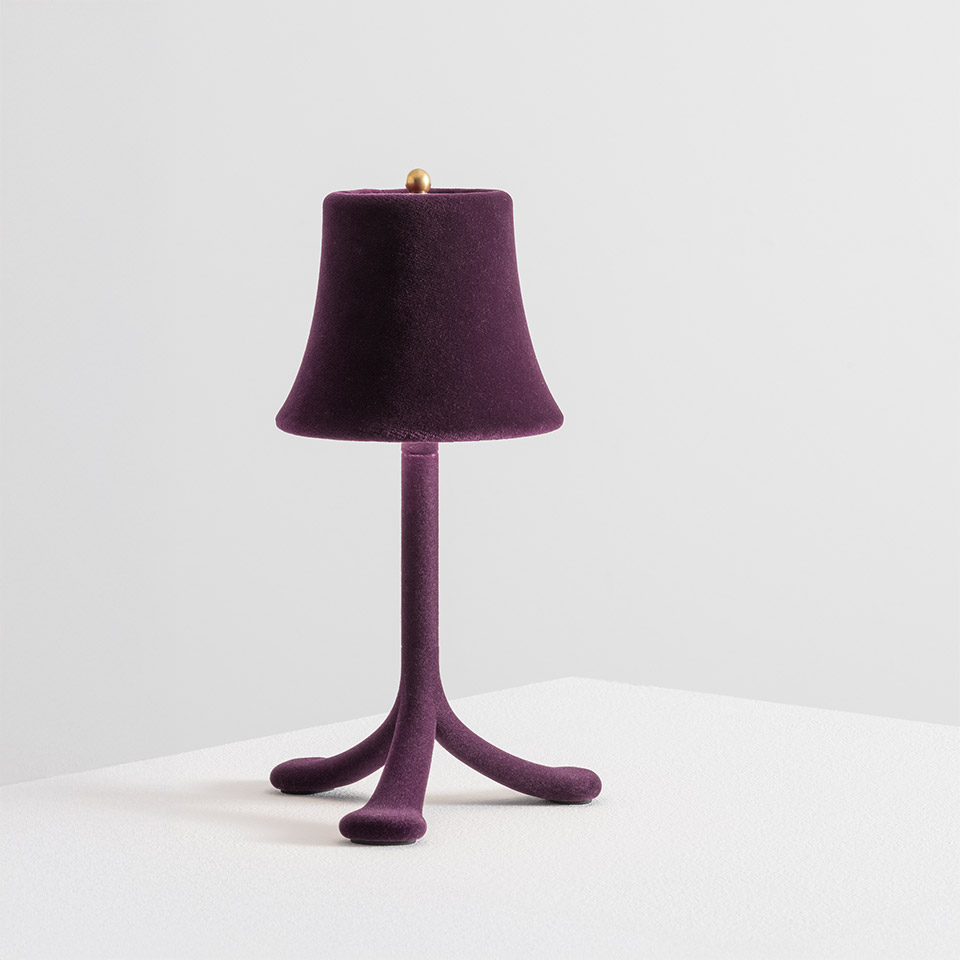 Lampada da tavolo Trois Rois di Artemide: base a treppiede in velluto viola con gambe curve organiche, paralume a campana coordinato, finale dorato in cima